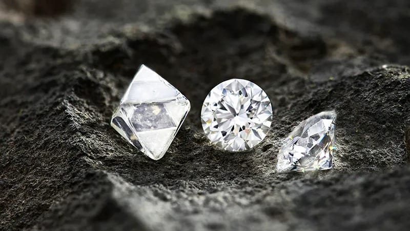 Natural diamond rough and polished stones on dark rock